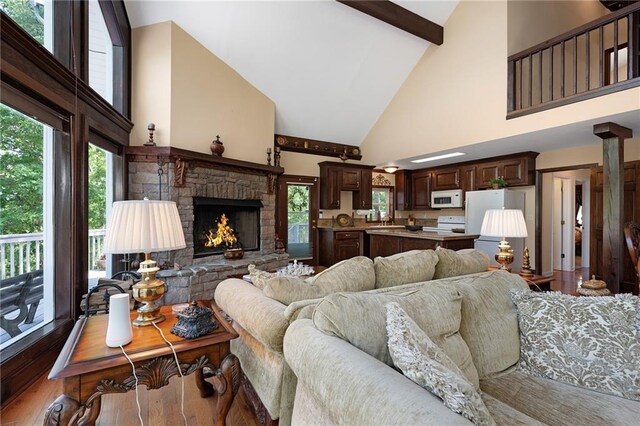 living room featuring a fireplace, hardwood / wood-style flooring, high vaulted ceiling, and plenty of natural light