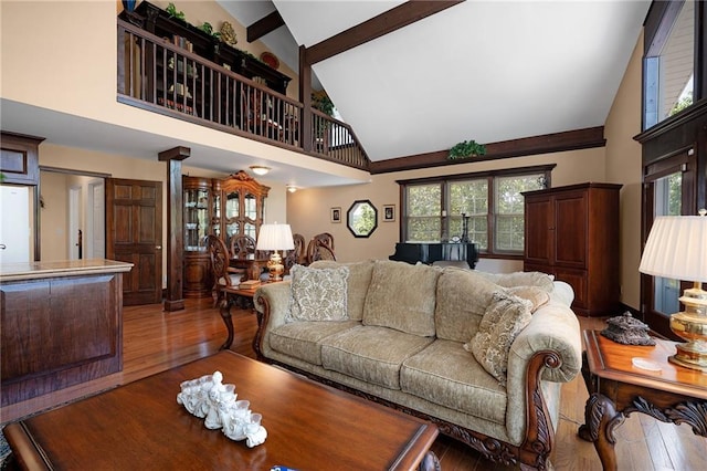 living room featuring a wealth of natural light, wood-type flooring, and high vaulted ceiling