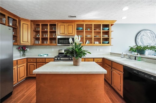 70 Lake Charles Xing, Covington, GA 30016 - kitchen featuring appliances with stainless steel finishes, a sink, open shelves, a textured ceiling, and wood finished floors