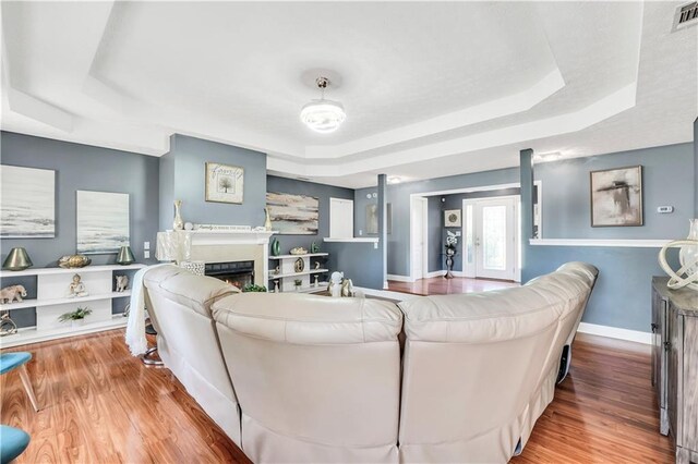 70 Lake Charles Xing, Covington, GA 30016 - living area featuring a tray ceiling, wood finished floors, a lit fireplace, and baseboards