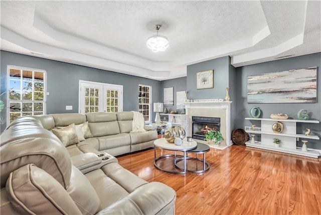 70 Lake Charles Xing, Covington, GA 30016 - living room featuring a raised ceiling, wood finished floors, a fireplace with flush hearth, and a textured ceiling