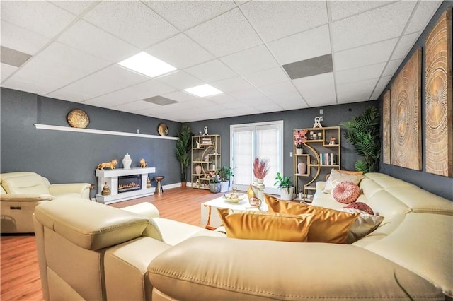 70 Lake Charles Xing, Covington, GA 30016 - living room featuring wood finished floors, a drop ceiling, a glass covered fireplace, and baseboards