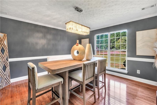 70 Lake Charles Xing, Covington, GA 30016 - dining area with a chandelier, hardwood / wood-style flooring, baseboards, a textured ceiling, and ornamental molding