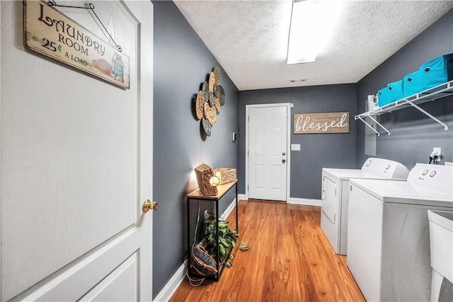 70 Lake Charles Xing, Covington, GA 30016 - laundry room featuring washing machine and clothes dryer, baseboards, light wood-style floors, and a textured ceiling
