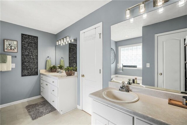 70 Lake Charles Xing, Covington, GA 30016 - full bathroom with two vanities, baseboards, a garden tub, and tile patterned floors