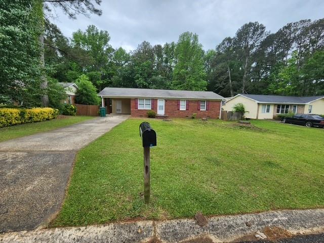 ranch-style home with fence, an attached carport, driveway, and a front yard