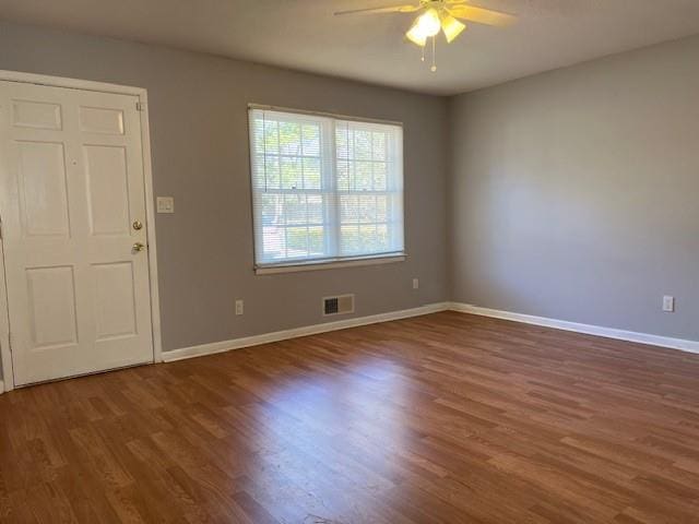 empty room featuring baseboards, ceiling fan, visible vents, and wood finished floors