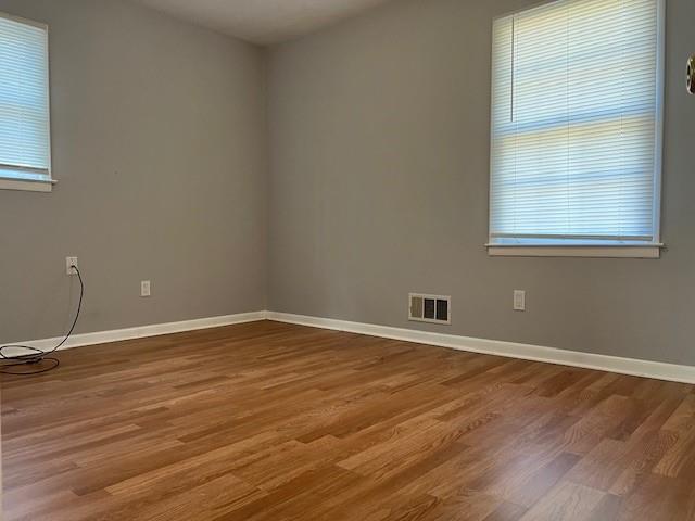 spare room with baseboards, visible vents, and a healthy amount of sunlight