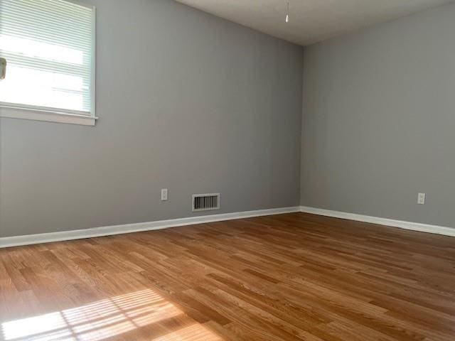 spare room with baseboards, wood finished floors, and visible vents