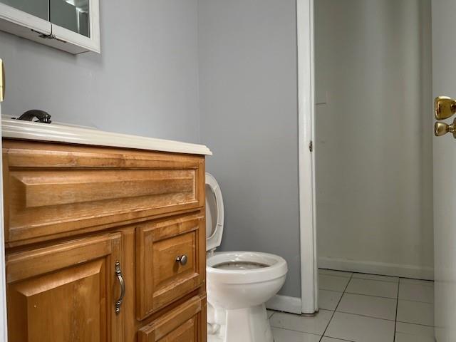 half bathroom featuring tile patterned flooring, baseboards, and toilet