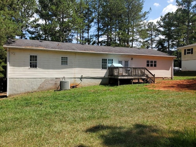 rear view of house featuring central AC unit, a wooden deck, and a yard