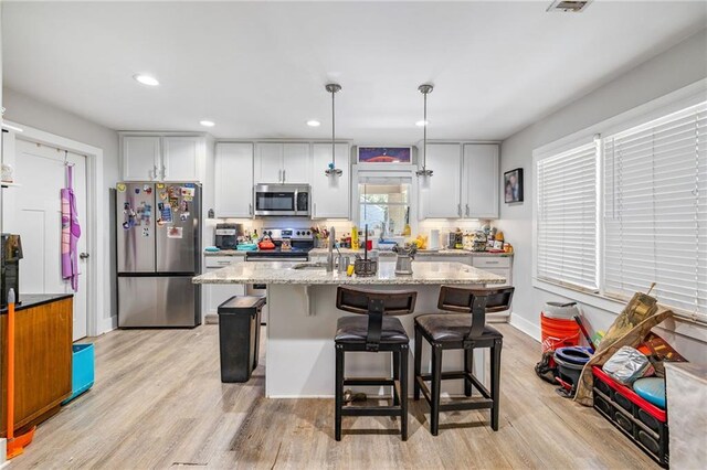 312 Glen Iris Dr, Monroe, GA 30655 - kitchen featuring stainless steel appliances, light wood-style flooring, an island with sink, light stone counters, and recessed lighting
