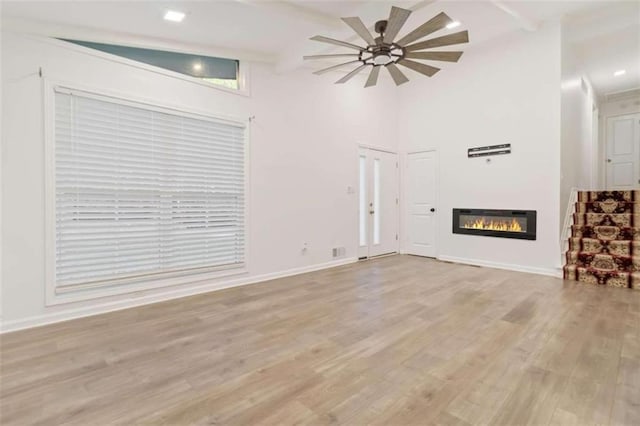 unfurnished living room with light hardwood / wood-style flooring, vaulted ceiling with beams, and ceiling fan