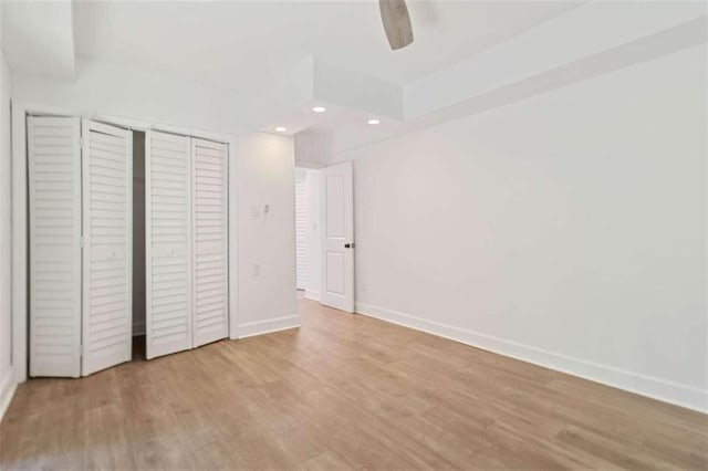 unfurnished bedroom featuring light hardwood / wood-style floors, ceiling fan, and a closet