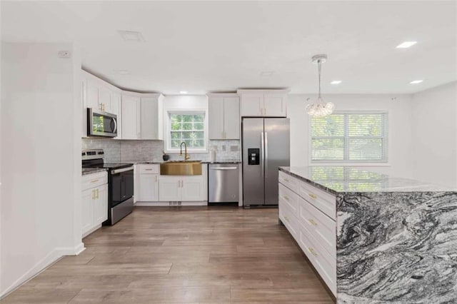 kitchen featuring stainless steel appliances, white cabinetry, hardwood / wood-style floors, and sink