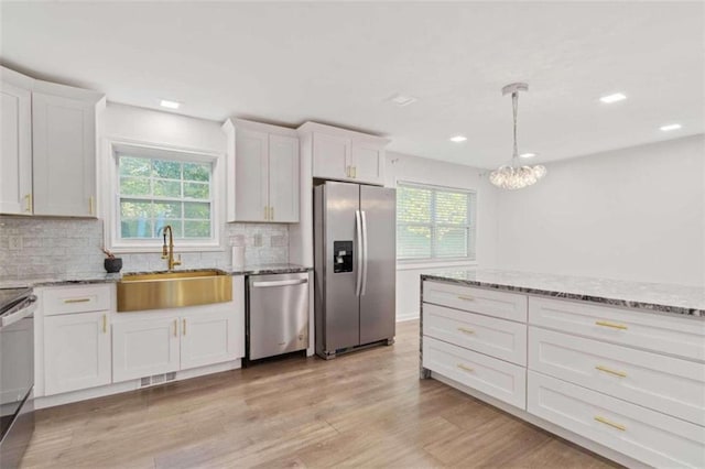 kitchen featuring white cabinetry, appliances with stainless steel finishes, a healthy amount of sunlight, and sink