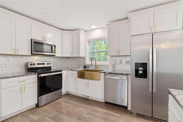 kitchen with white cabinetry, light hardwood / wood-style floors, appliances with stainless steel finishes, and sink