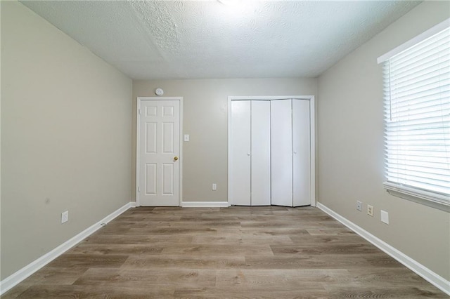 unfurnished bedroom featuring visible vents, baseboards, wood finished floors, and a closet
