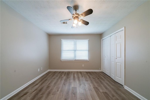 unfurnished bedroom with a ceiling fan, baseboards, wood finished floors, and a closet