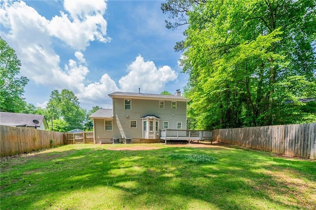 view of yard with a fenced backyard, a deck, and central AC unit