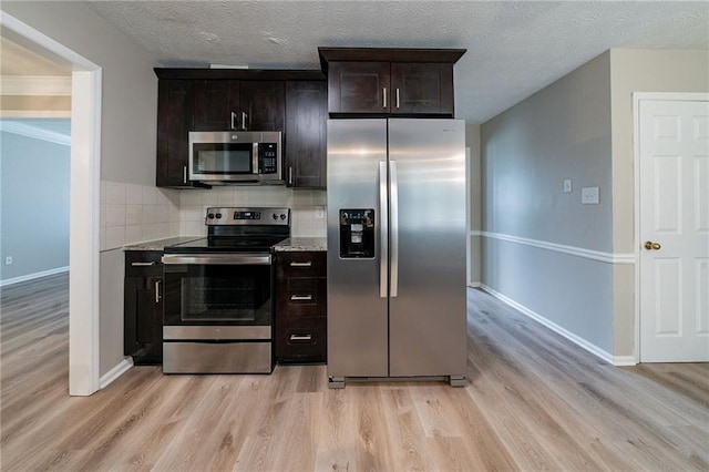 kitchen featuring dark brown cabinets, stainless steel appliances, baseboards, decorative backsplash, and light wood-type flooring