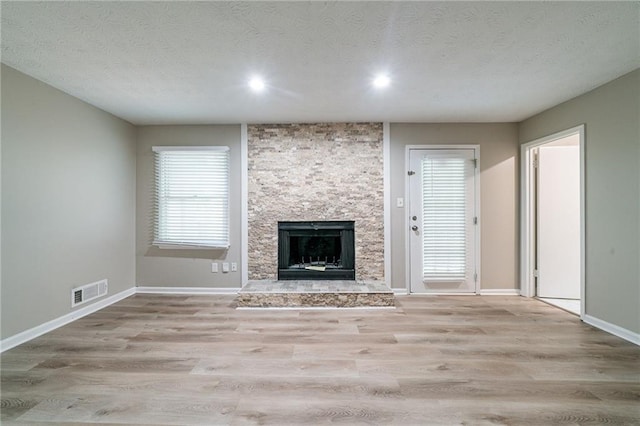 unfurnished living room with visible vents, a fireplace, wood finished floors, baseboards, and recessed lighting