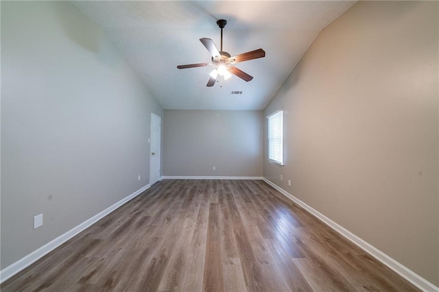 spare room with a ceiling fan, baseboards, vaulted ceiling, and wood finished floors
