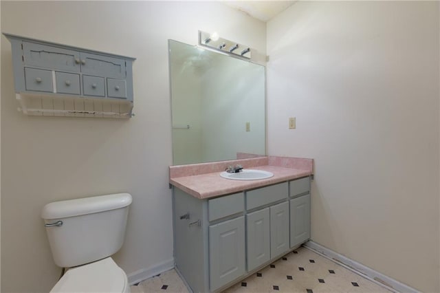 half bathroom featuring toilet, tile patterned floors, baseboards, and vanity