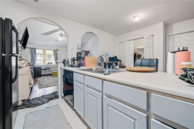 kitchen with sink, a textured ceiling, ceiling fan, and black appliances