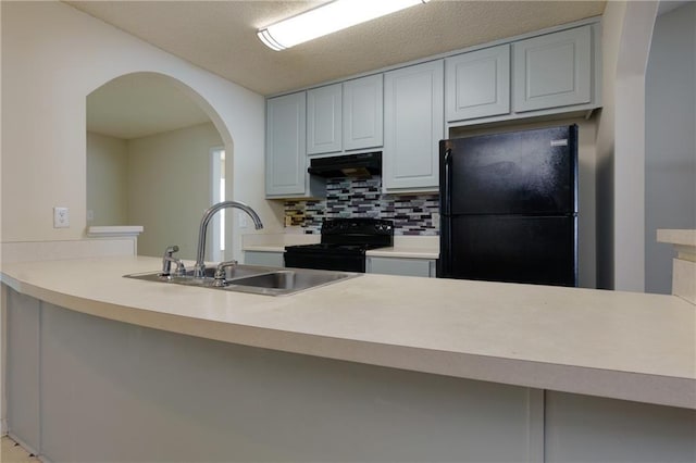 kitchen featuring black appliances, under cabinet range hood, light countertops, and a sink