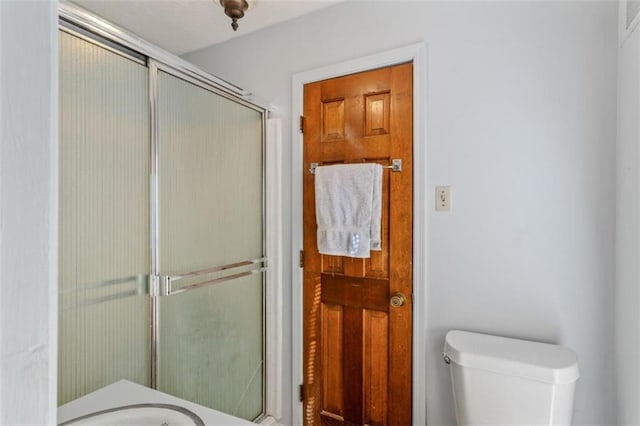 bathroom with toilet and a shower with shower door