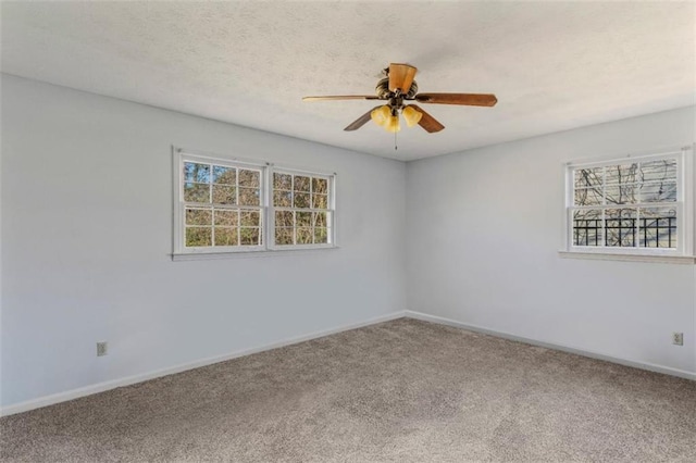 carpeted spare room featuring a wealth of natural light and ceiling fan