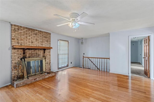 unfurnished living room featuring a brick fireplace, hardwood / wood-style flooring, and ceiling fan