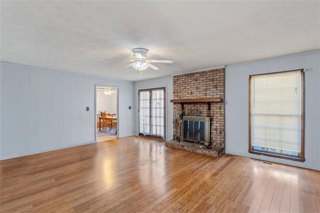 unfurnished living room with a fireplace, ceiling fan, and light hardwood / wood-style flooring