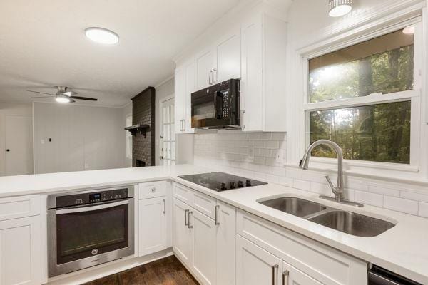 kitchen with black appliances, decorative backsplash, sink, white cabinetry, and dark wood-type flooring