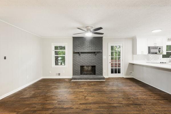 unfurnished living room featuring ceiling fan, dark hardwood / wood-style flooring, and a fireplace