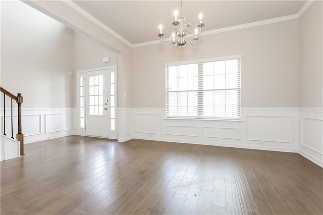 foyer entrance with dark wood-type flooring, crown molding, and a notable chandelier