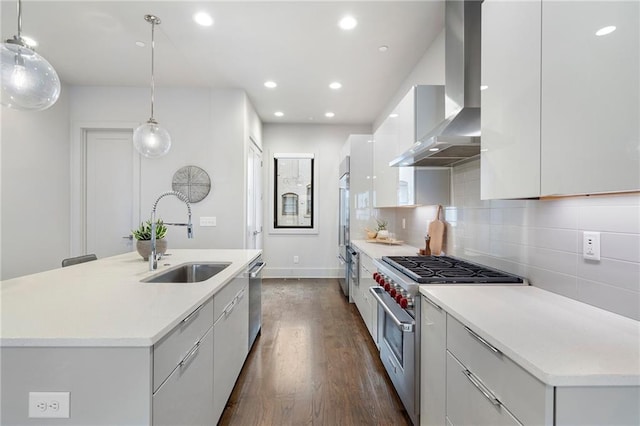 kitchen featuring premium appliances, a sink, wall chimney range hood, and modern cabinets