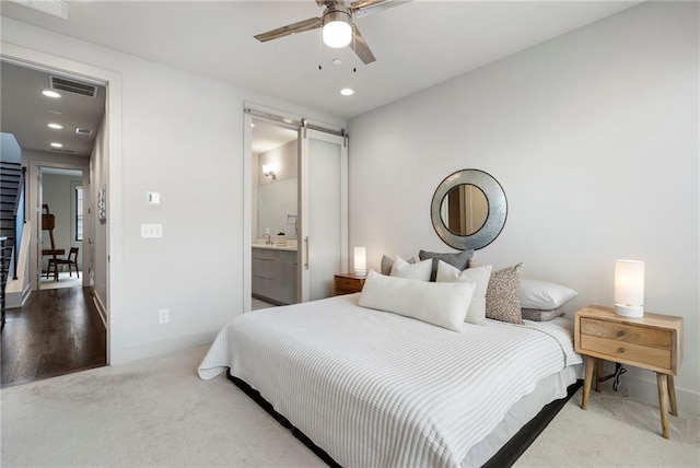 carpeted bedroom featuring recessed lighting, a barn door, ceiling fan, ensuite bath, and baseboards