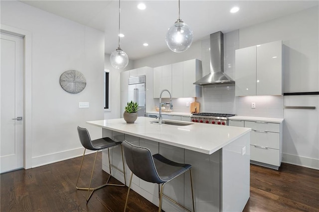 kitchen with a sink, white cabinets, wall chimney range hood, appliances with stainless steel finishes, and backsplash