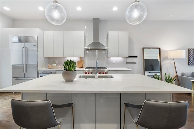 kitchen with built in fridge, backsplash, white cabinets, wall chimney range hood, and modern cabinets