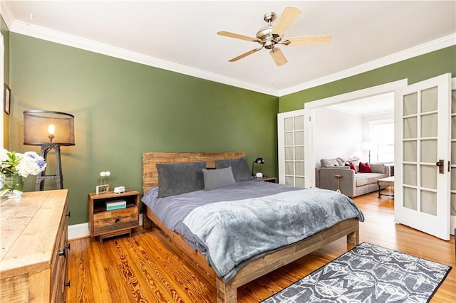 bedroom featuring ceiling fan, wood finished floors, baseboards, french doors, and crown molding