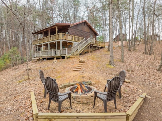 rear view of property with a deck, stairs, and an outdoor fire pit