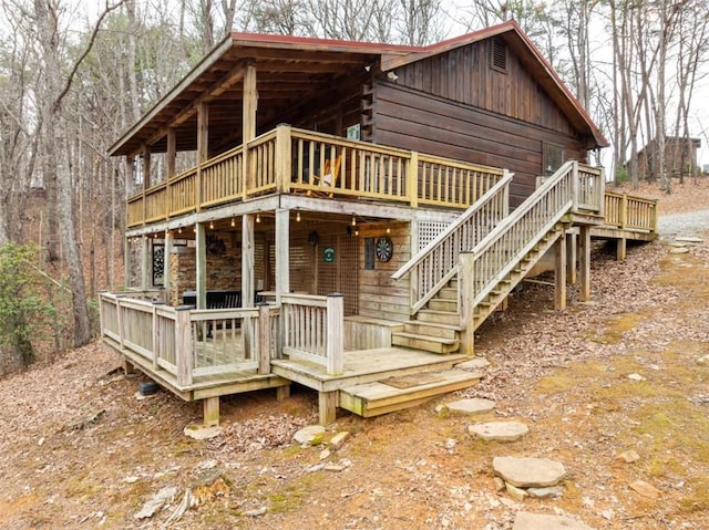 rear view of house featuring a wooden deck, log exterior, and stairs