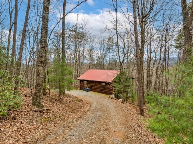 view of street with dirt driveway and a forest view
