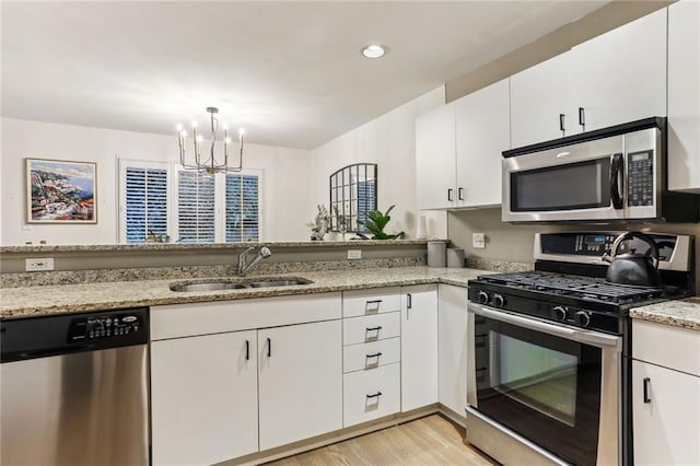 1209 Brookhaven Woods Ct NE, Brookhaven, GA 30319 - kitchen with stainless steel appliances, a sink, a chandelier, light wood-style flooring, and white cabinets