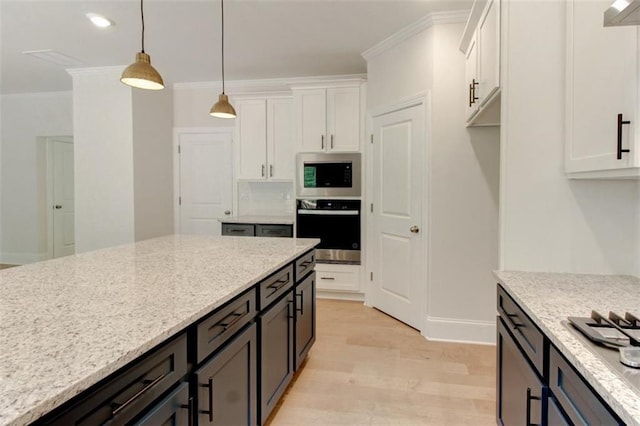 3292 Mill Forest Dr, Conyers, GA 30094 - kitchen featuring white cabinetry, light wood finished floors, stainless steel microwave, crown molding, and light stone countertops