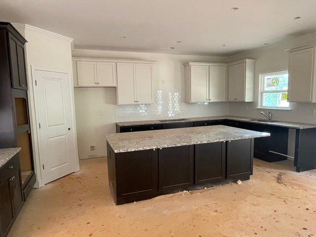 3292 Mill Forest Dr, Conyers, GA 30094 - kitchen with a kitchen island, a sink, and backsplash
