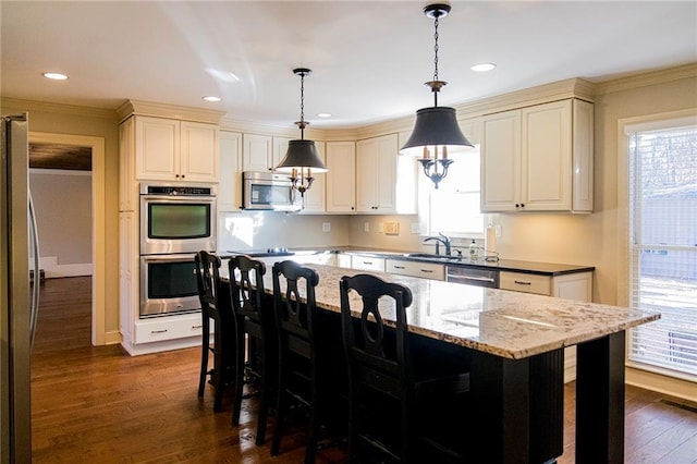 kitchen featuring dark wood-type flooring, hanging light fixtures, dark stone countertops, a wealth of natural light, and stainless steel appliances