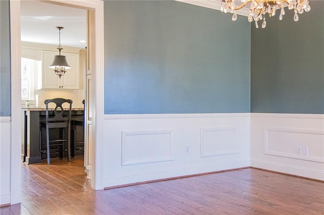 dining space with ornamental molding, a notable chandelier, and hardwood / wood-style flooring